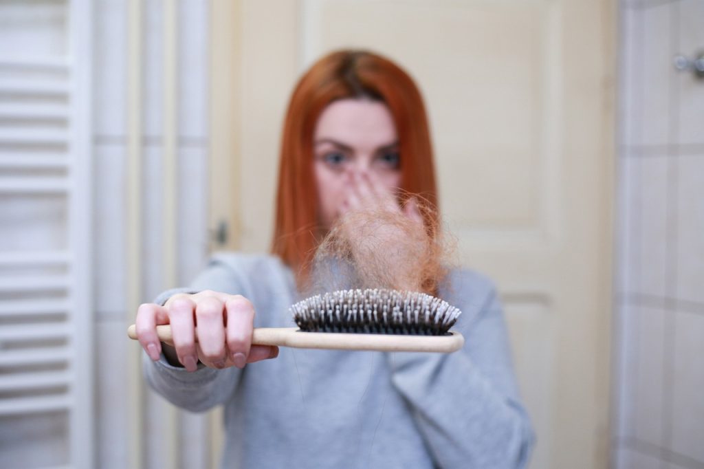 A woman holding a brush filled with hair