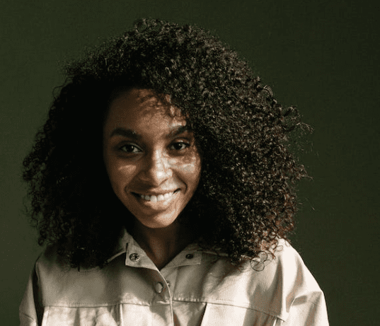 A young woman with curly dark hair smiling