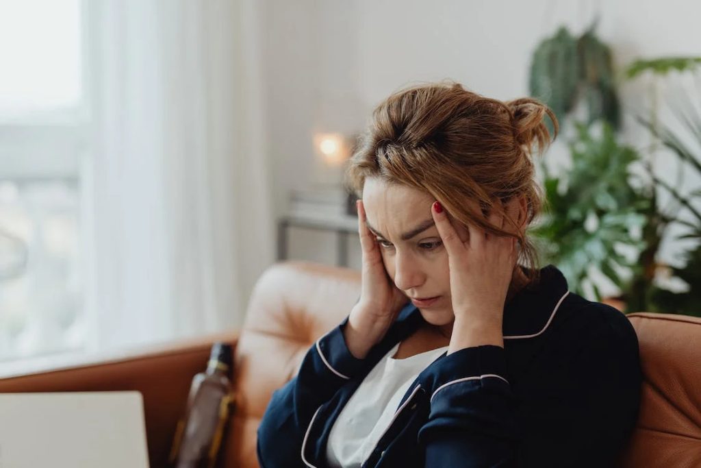 A woman sitting on a couch and holding her head