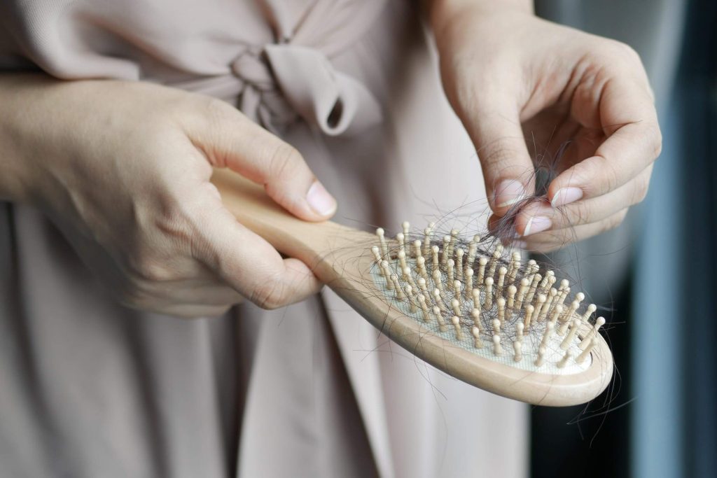 A woman removing hair from a hairbrush
