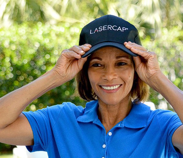 A Woman In Blue T-shirt Wearing And Holding A Lasercap