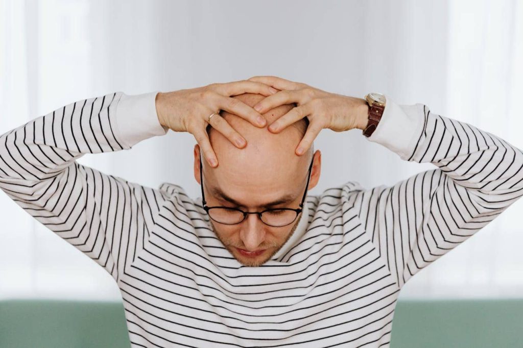 A bald man touching his head